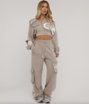 blonde lady wearing a taupe two piece taupe tracksuit with straight leg joggers