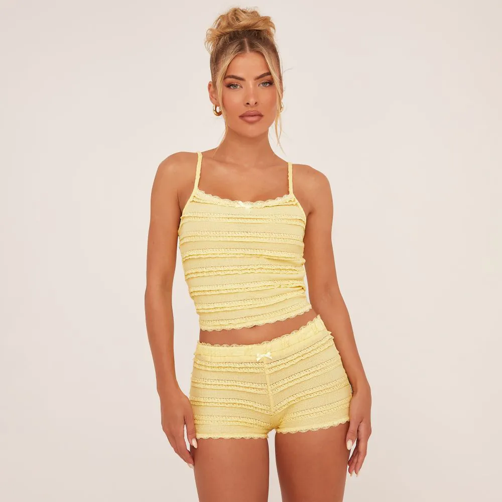 A frilly yellow co-ord with bow details. The top is a tank top with thin yellow straps and the shorts are low rise micro shorts.